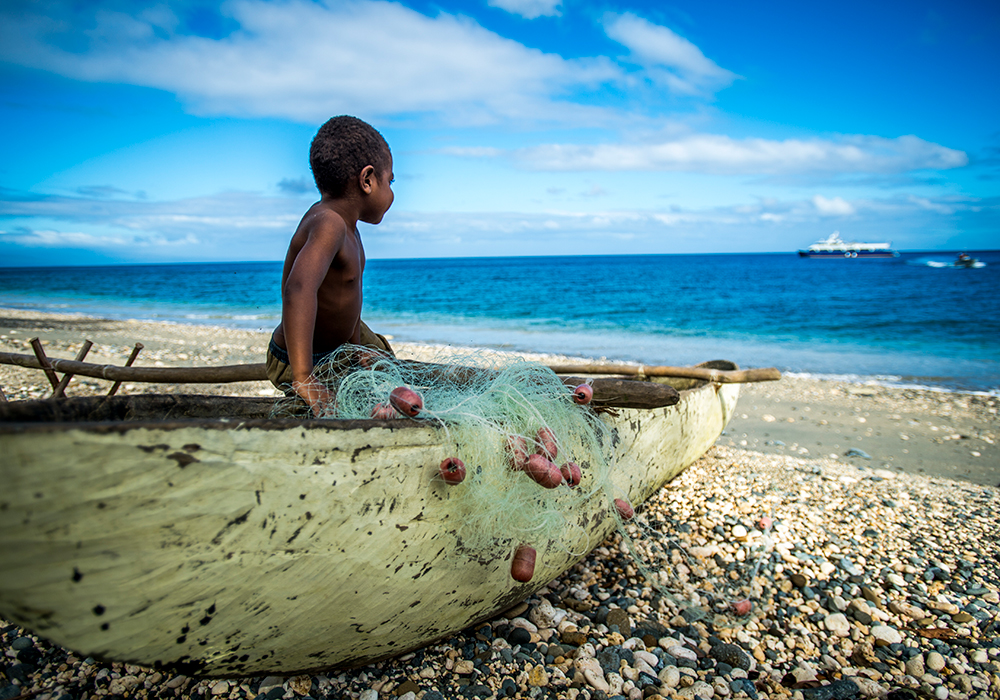 Vanuatu. Liten pojke som sitter i en liten båt